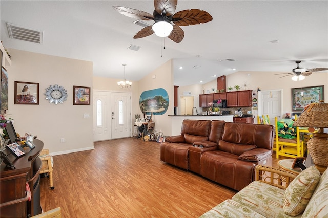 living room with lofted ceiling, ceiling fan with notable chandelier, and light hardwood / wood-style flooring