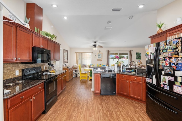 kitchen featuring vaulted ceiling, sink, decorative backsplash, black appliances, and light wood-type flooring