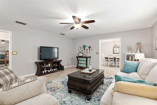 living room featuring ceiling fan with notable chandelier and light wood-type flooring