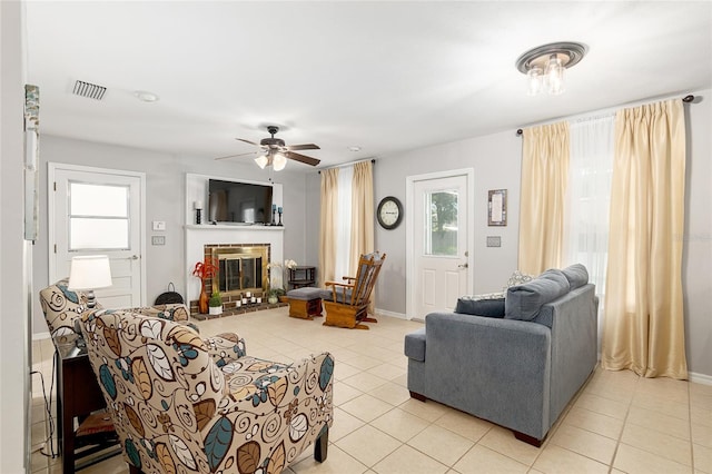 tiled living room with a healthy amount of sunlight, a fireplace, and ceiling fan