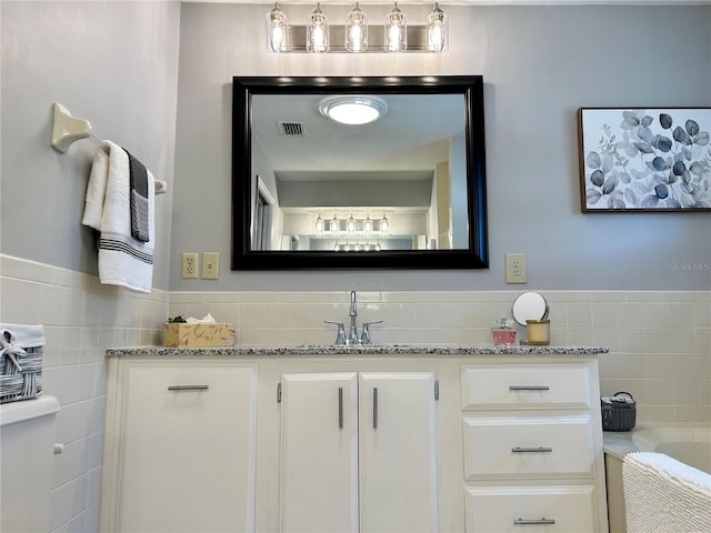 bathroom with vanity, tile walls, and a bathtub