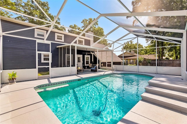 view of pool with glass enclosure, ceiling fan, and a patio area