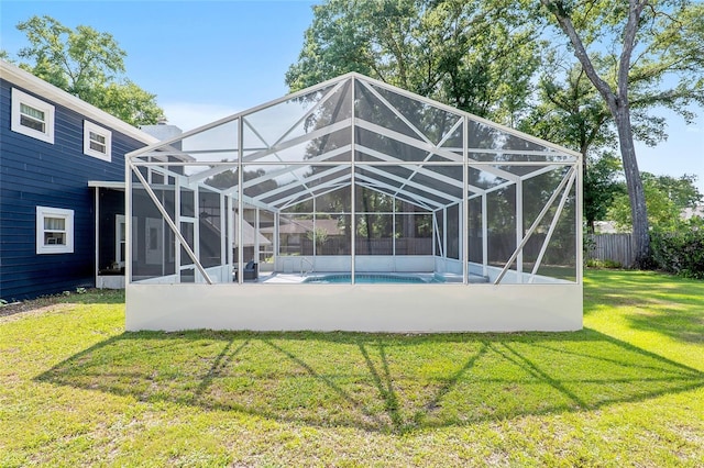 back of property featuring a yard, a fenced in pool, and glass enclosure