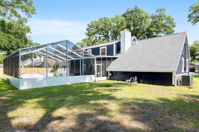 rear view of property with cooling unit, a yard, and a lanai