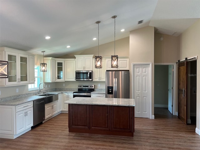 kitchen with pendant lighting, sink, a kitchen island, stainless steel appliances, and a barn door