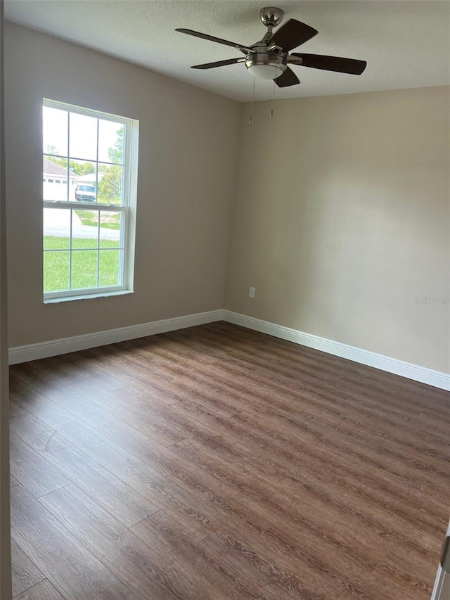 spare room with dark wood-type flooring and ceiling fan