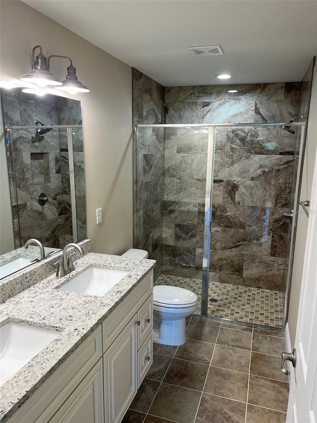 bathroom featuring tile patterned flooring, vanity, toilet, and a shower with door