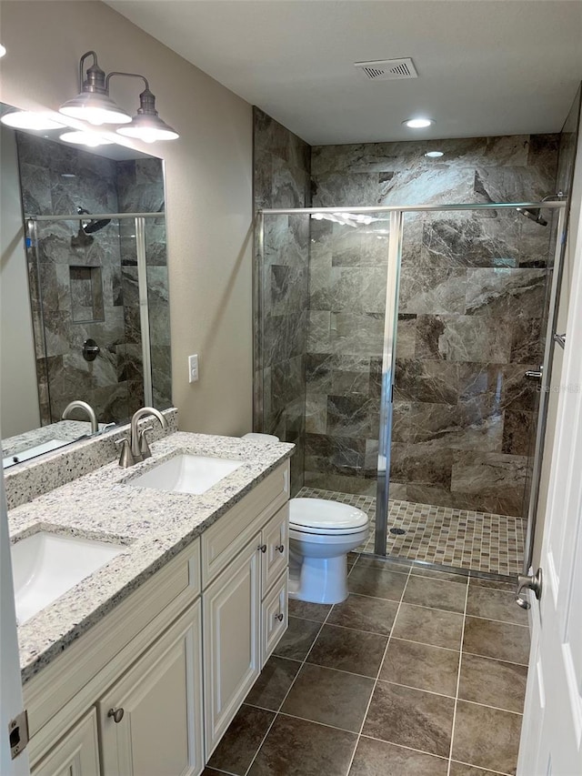 bathroom with tile patterned flooring, a shower with shower door, vanity, and toilet