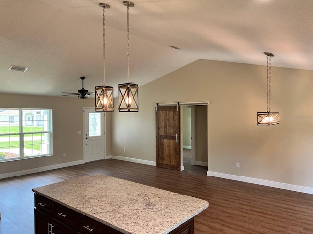 kitchen with a barn door, dark hardwood / wood-style floors, ceiling fan, and pendant lighting