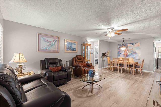 living room featuring ceiling fan, a textured ceiling, and light hardwood / wood-style flooring