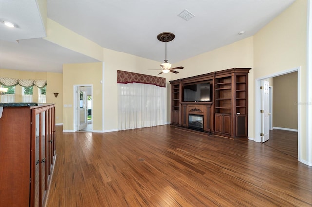 unfurnished living room featuring ceiling fan and dark wood-type flooring