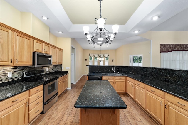 kitchen featuring appliances with stainless steel finishes, light hardwood / wood-style floors, a center island, and an inviting chandelier