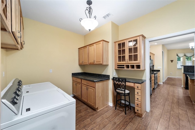 clothes washing area featuring washing machine and clothes dryer, dark hardwood / wood-style floors, and cabinets