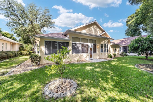 rear view of house featuring a lawn and a sunroom