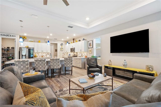 living room with ceiling fan, ornamental molding, and light hardwood / wood-style floors