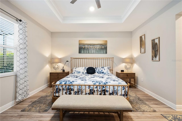 bedroom featuring a raised ceiling, light hardwood / wood-style floors, crown molding, and ceiling fan