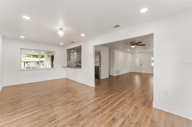 unfurnished living room featuring light wood-type flooring, ceiling fan, and sink