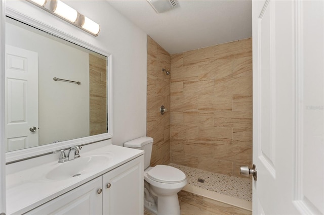 bathroom with vanity, toilet, and tiled shower