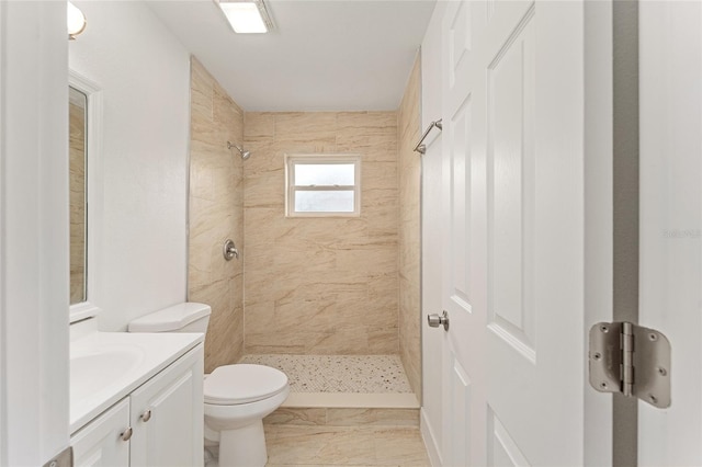 bathroom featuring tiled shower, vanity, and toilet