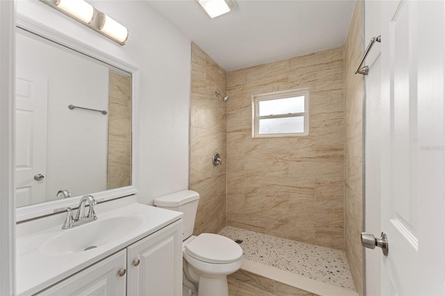 bathroom featuring vanity, toilet, and tiled shower