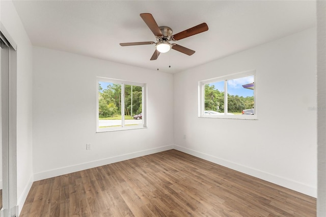 empty room with a wealth of natural light, ceiling fan, and hardwood / wood-style flooring