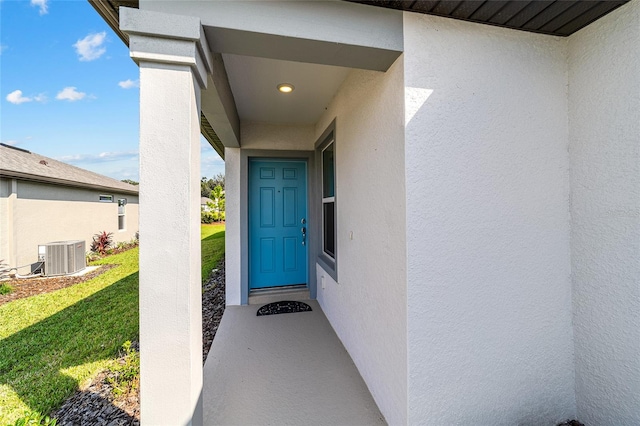 property entrance with a lawn and cooling unit