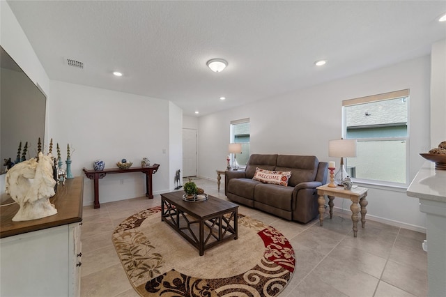 living room with a textured ceiling, plenty of natural light, and light tile patterned flooring