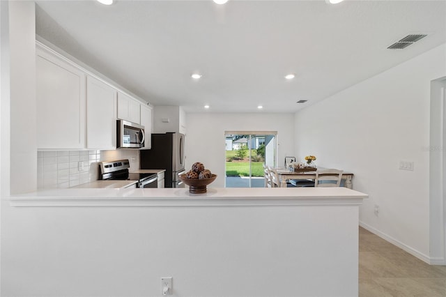 kitchen with white cabinetry, kitchen peninsula, decorative backsplash, light tile patterned flooring, and appliances with stainless steel finishes