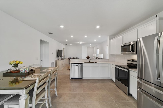 kitchen featuring kitchen peninsula, sink, white cabinets, and stainless steel appliances