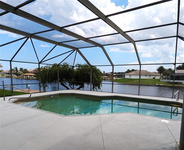 view of pool featuring glass enclosure, a water view, and a patio area