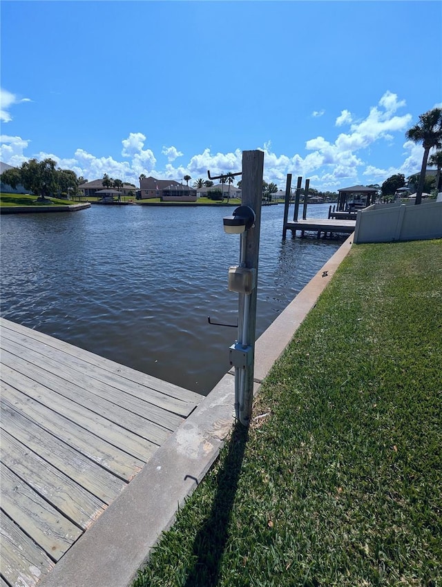 dock area with a lawn and a water view