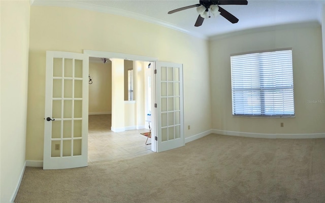 carpeted spare room featuring ornamental molding, ceiling fan, and french doors