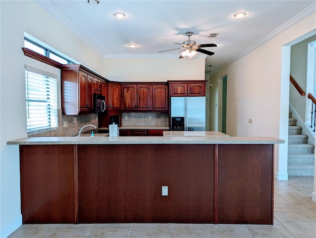 kitchen with appliances with stainless steel finishes, crown molding, kitchen peninsula, and tasteful backsplash