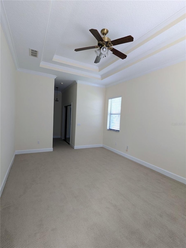 carpeted empty room with ceiling fan, a raised ceiling, and crown molding