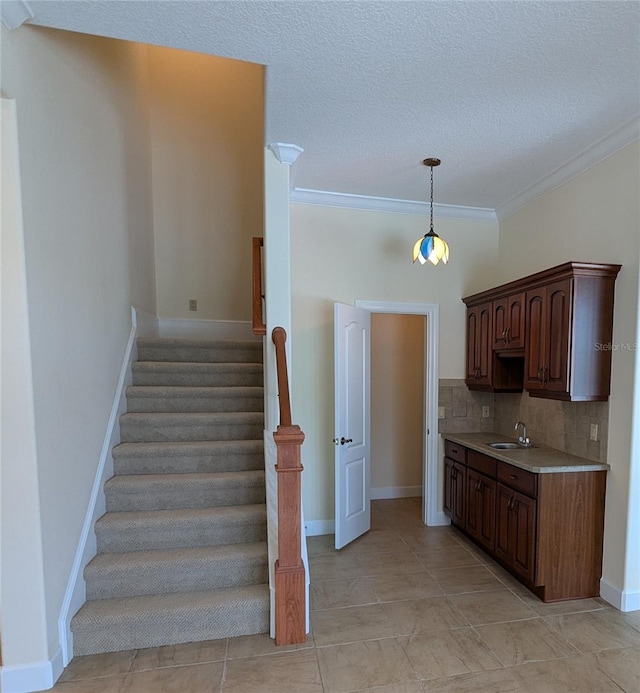 staircase featuring a textured ceiling, tile patterned flooring, ornamental molding, and sink