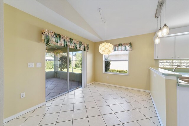 unfurnished dining area with light tile patterned flooring, vaulted ceiling, and a wealth of natural light