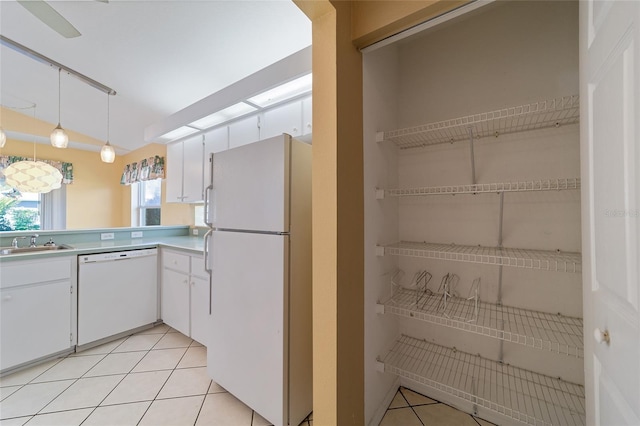 kitchen featuring pendant lighting, sink, white cabinets, white appliances, and light tile patterned floors