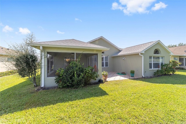 rear view of property featuring a sunroom, a lawn, and a patio area