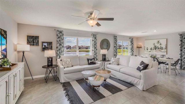 living room featuring ceiling fan, a textured ceiling, and light tile patterned floors