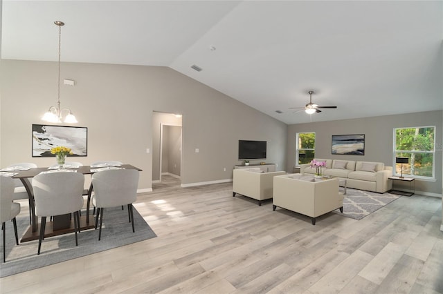 living room with light wood-type flooring, ceiling fan with notable chandelier, and vaulted ceiling