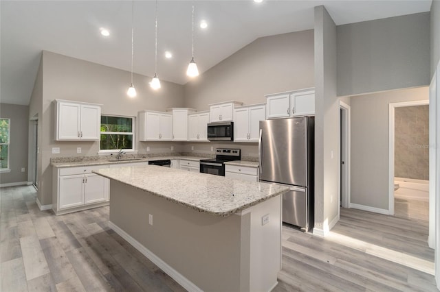 kitchen with appliances with stainless steel finishes, white cabinetry, a healthy amount of sunlight, and a kitchen island