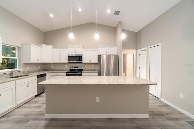 kitchen featuring appliances with stainless steel finishes, hanging light fixtures, a center island, and sink