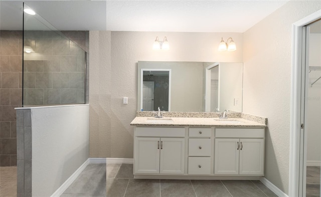 bathroom with a tile shower, vanity, and tile patterned floors