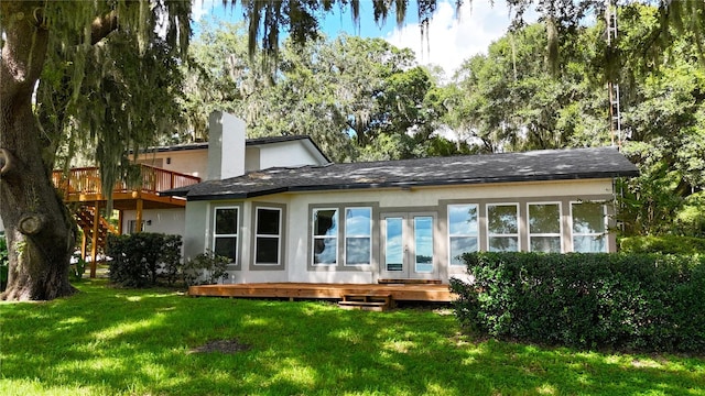 rear view of property featuring a deck and a lawn