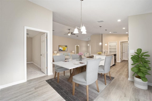 dining space with ceiling fan, sink, light hardwood / wood-style flooring, and vaulted ceiling