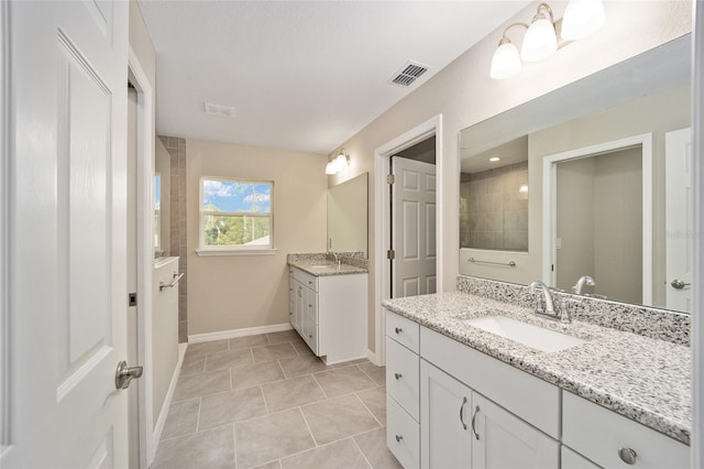 bathroom with tile patterned flooring, tiled shower, and vanity