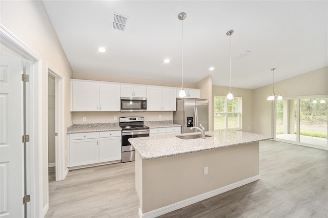 kitchen featuring a center island with sink, white cabinetry, appliances with stainless steel finishes, light wood-type flooring, and vaulted ceiling