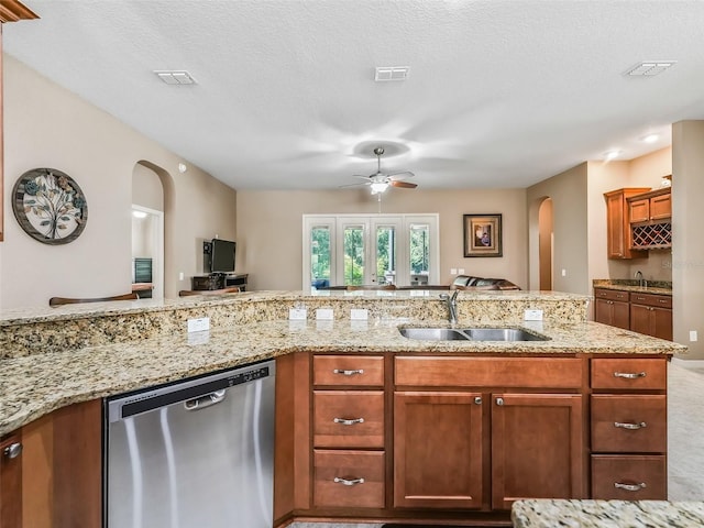 kitchen with sink, ceiling fan, light stone counters, a textured ceiling, and stainless steel dishwasher