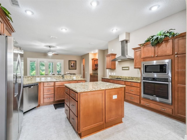 kitchen featuring sink, a center island, kitchen peninsula, stainless steel appliances, and wall chimney range hood