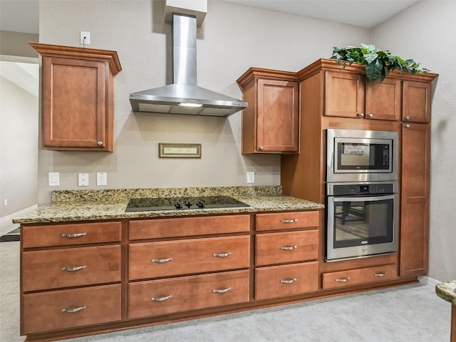 kitchen with light stone counters, wall chimney range hood, and appliances with stainless steel finishes